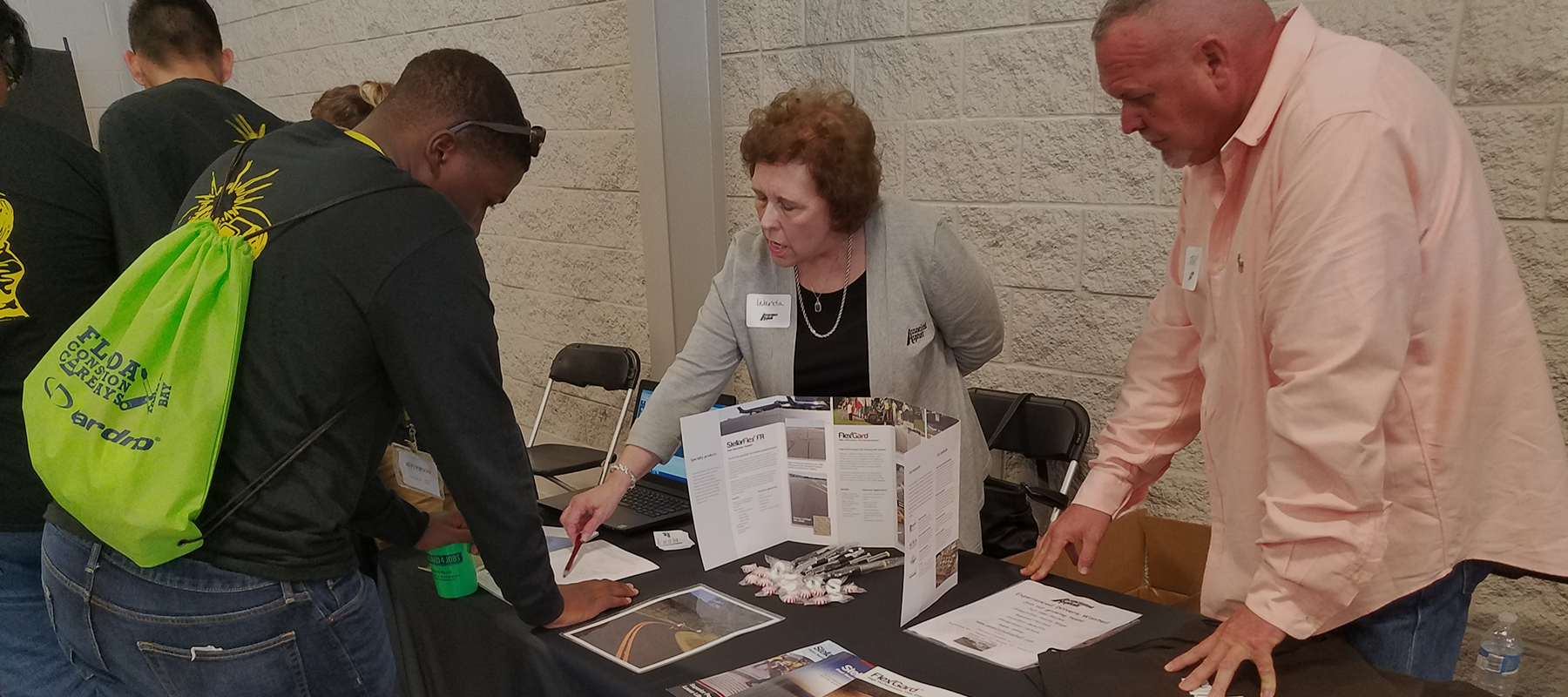 A group of Associated Asphalt employees working a table at the Florida Construction Career Day with people visiting the table.
