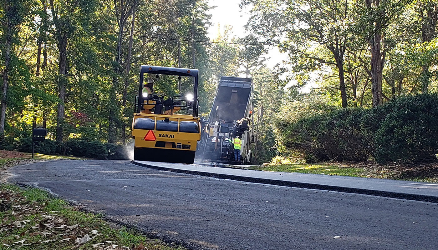 A roller and a dump truck repaving a residential street in York County.